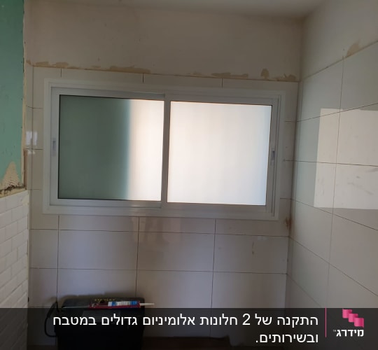חלון אלומיניום עם מסגרת לבנה על קיר מרוצף